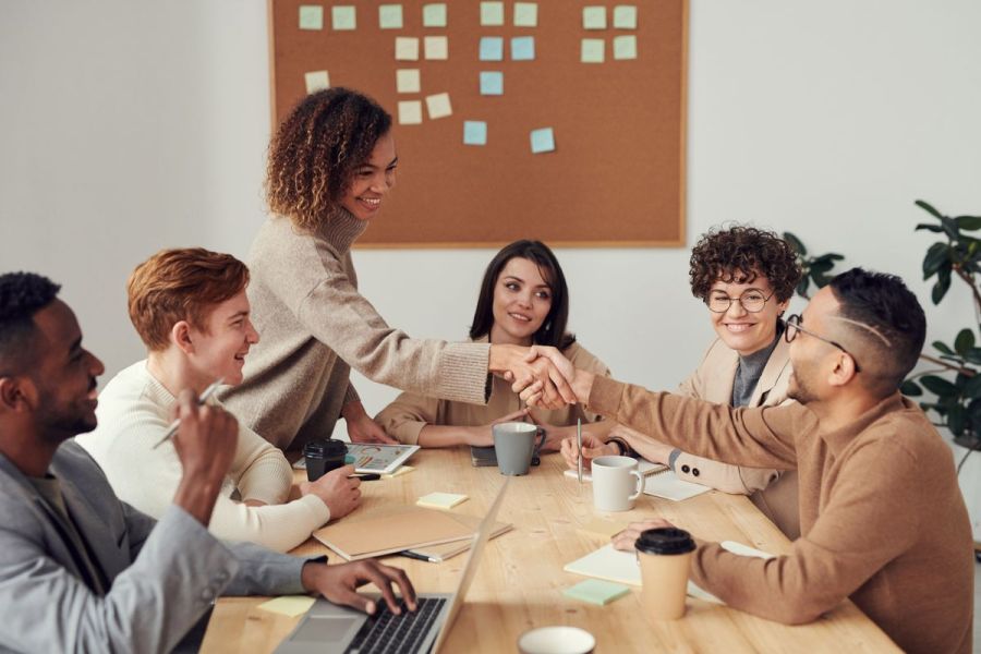 Team meeting around a table ending with a handshake